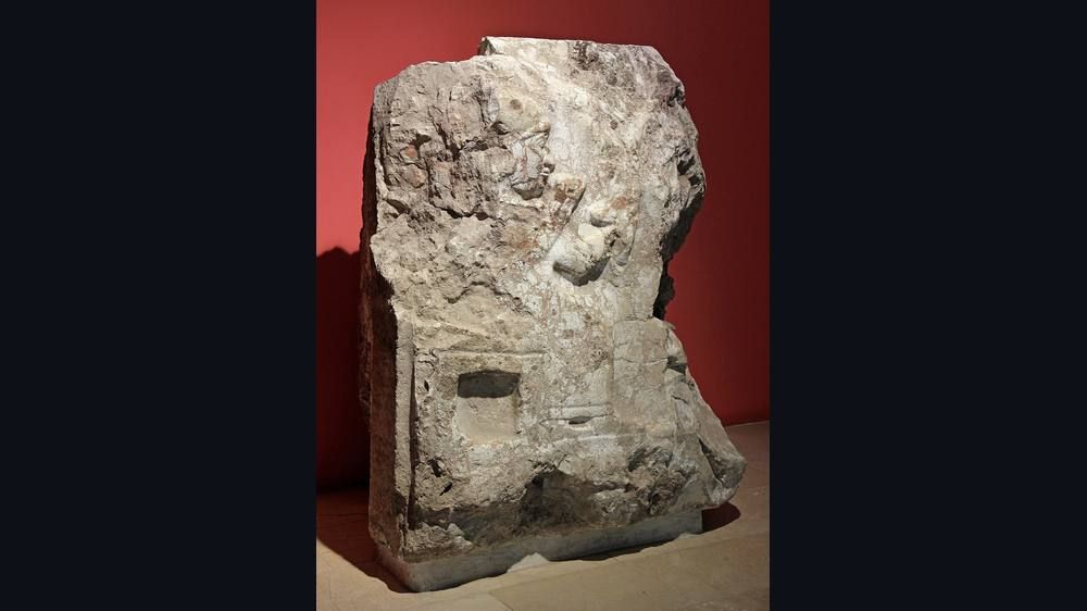 Carved stone relief of a seated figure in a museum display.
