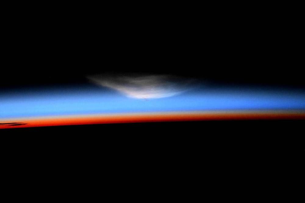 A thin glowing band of light lies along the curved horizon of the Earth against black space, seen from orbit.