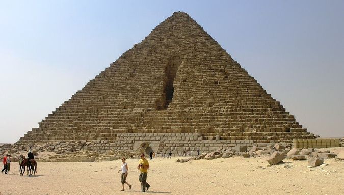 The Pyramid of Menkaure at Giza under a blue sky, with a smaller subsidiary pyramid beside it.