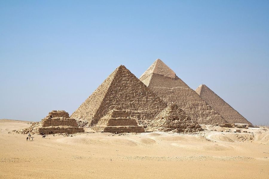 Aerial view of the three main pyramids of Giza, with the smaller queens' pyramids in front, on the desert plateau.